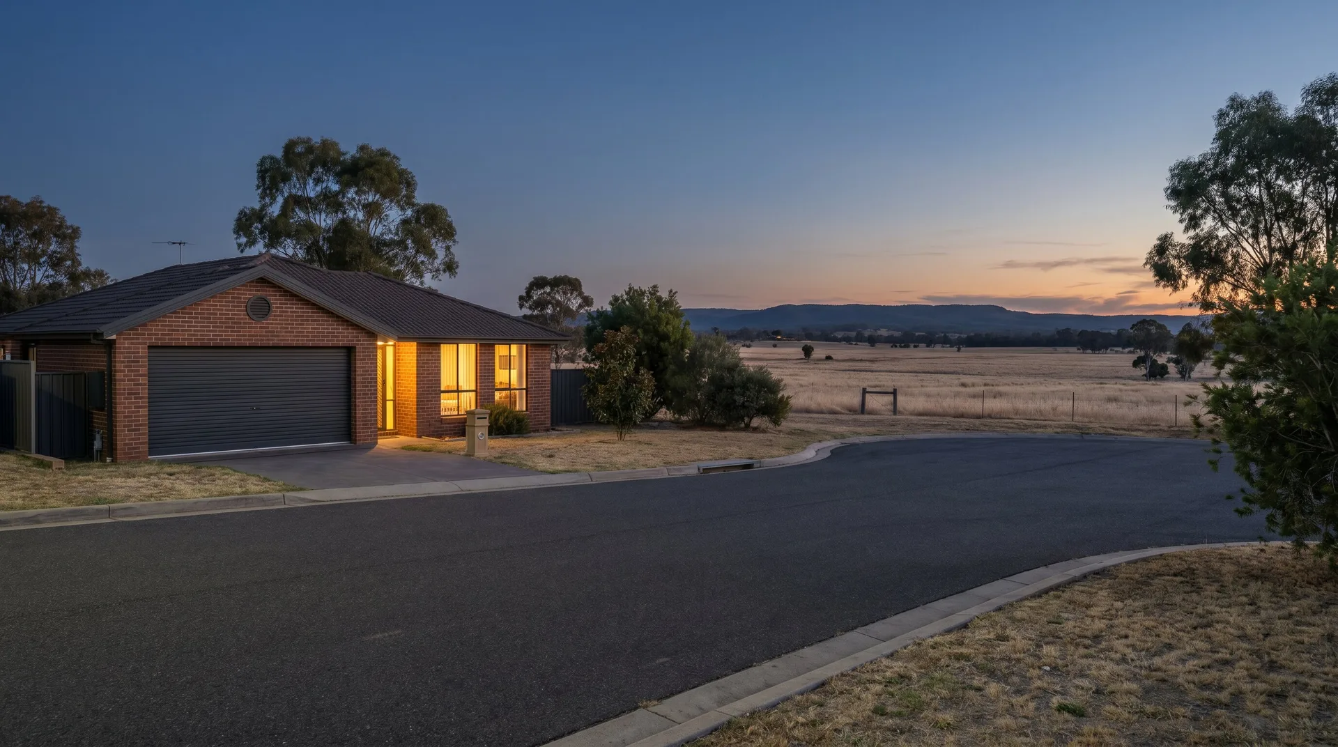 A Singleton house at dusk with the garage door closed and the windows lit